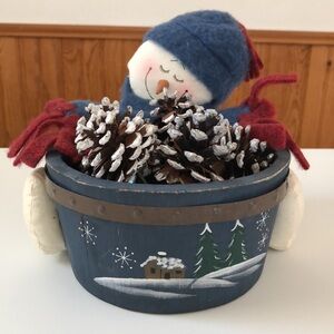 Snowman with wooden bucket with pine cones